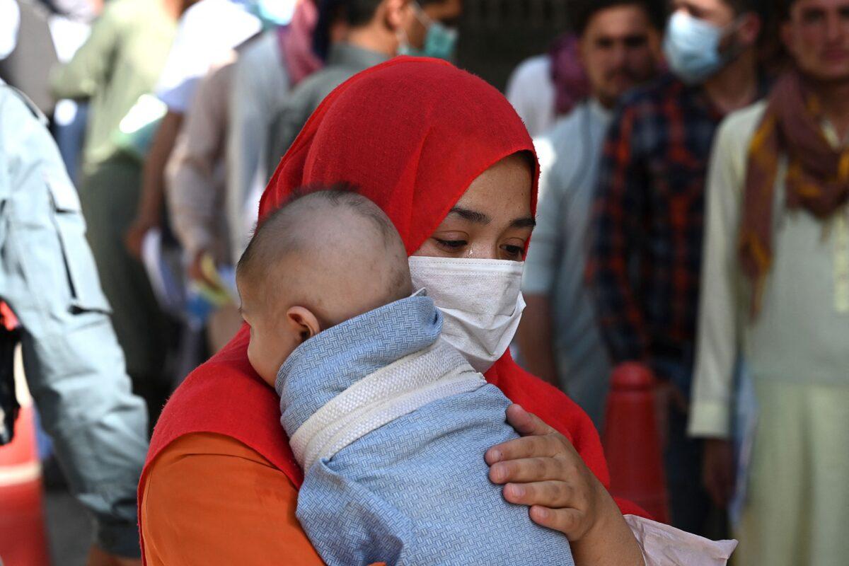 A woman with a child stands in a queue along with others to submit their passport applications at an office in Kabul, Afghanistan, on July 25, 2021. (Sajjad Hussain/AFP via Getty Images)