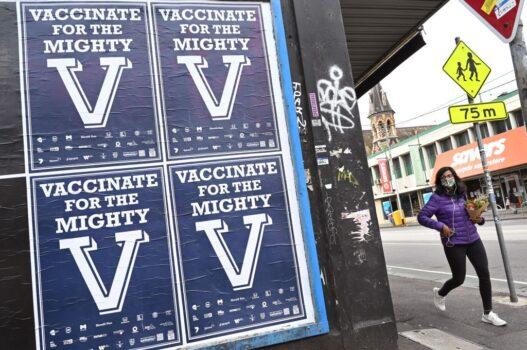 A person walks past posters encouraging people to get vaccinated in Melbourne, Australia, on Aug. 31, 2021. (William West/AFP via Getty Images)