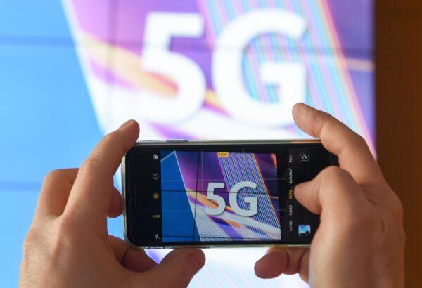 A journalist takes pictures of a projection screen prior to the start of Germany's auction for the construction of an ultra-fast 5G mobile network at the German Federal Network Agency (BNA, Bundesnetzagentur) in Mainz, western Germany, on March 19, 2019. (Arne Dedert /DPA/AFP via Getty Images)