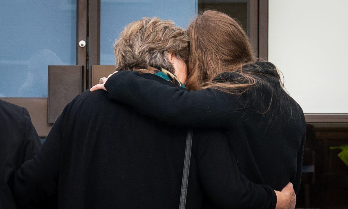 Julia Amess, the widow of Conservative MP Sir David Amess, holds one of their daughters as they view flowers and tributes left for her late husband at Belfairs Methodist Church in Eastwood Road North, Leigh-on-Sea, England, on Oct. 18, 2021. (Aaron Chown/PA)