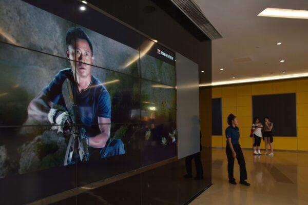 A woman walks past a video screen showing scenes from the movie "Wolf Warrior 2" outside a theater in Beijing on Aug. 21, 2017. (Greg Baker/AFP via Getty Images)