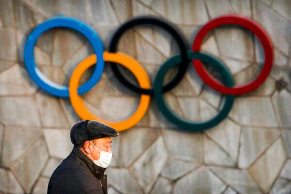 A man walks past the Olympic rings on the exterior of a venue for the upcoming 2022 Winter Olympics in Beijing on Feb. 2, 2021. (Mark Schiefelbein/AP Photo)