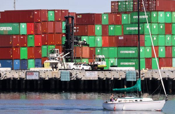 A sailboat passes cargo containers stacked at the Port of Los Angeles, the nation’s busiest container port, in San Pedro, Calif., on Oct. 15, 2021. (Mario Tama/Getty Images)