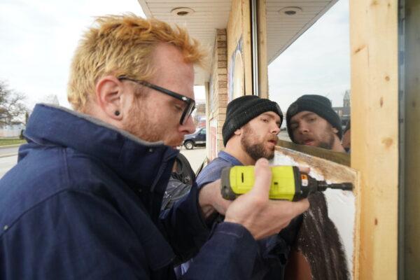 Kenoshan Kevin Page puts up plywood barricades in front of a business in Kenosha, Wis., on Nov. 20, 2021. (Jackson Elliott/The Epoch Times)