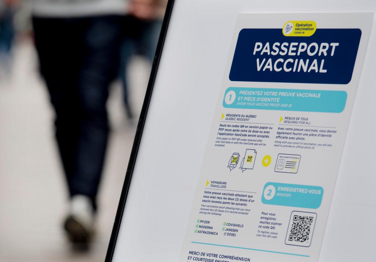 People walk by a sign at a restaurant advising customers of Quebec’s COVID-19 vaccine passport in Montreal on Sept. 6, 2021. (The Canadian Press/Graham Hughes)