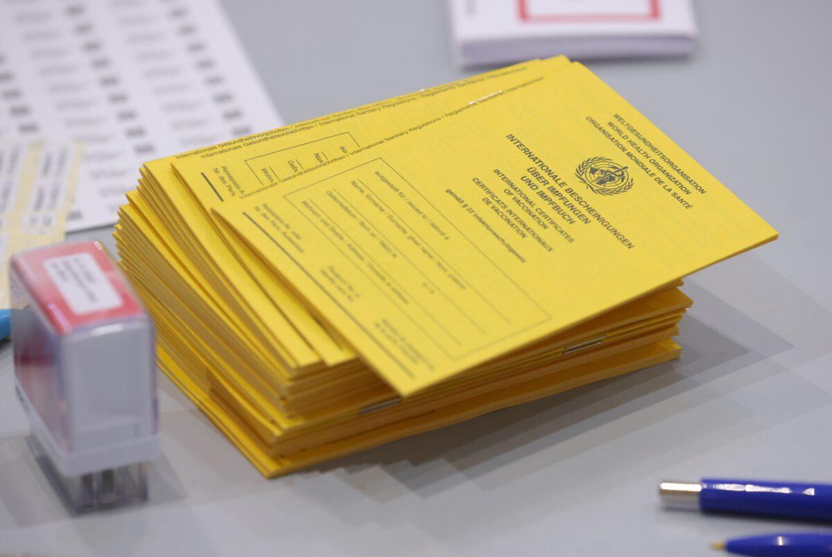 Blank yellow vaccination booklets lie on a registration table for people arriving to get COVID-19 vaccines at a church in Berlin, Germany, on Dec. 15, 2021. (Sean Gallup/Getty Images)