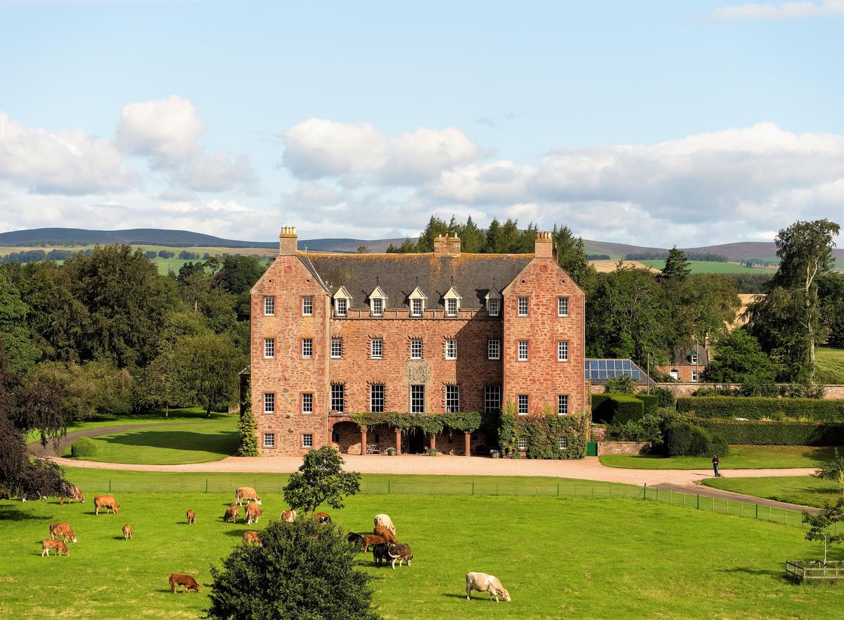 The distinctive red sandstone front façade of Careston Castle. This magnificent Scottish manor home is surrounded by lush gardens, mature policy parkland, and mature woodlands. (Courtesy of Itago Media Ltd.)