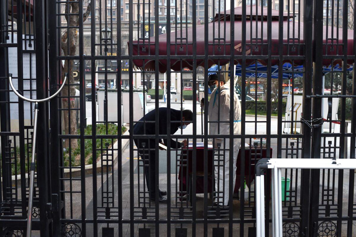 A security guard checks information of a resident at the entrance of a residental area that is under restrictions following a recent coronavirus outbreak in Xian, in China's northern Shaanxi province on Dec. 23, 2021. (STR/AFP via Getty Images)