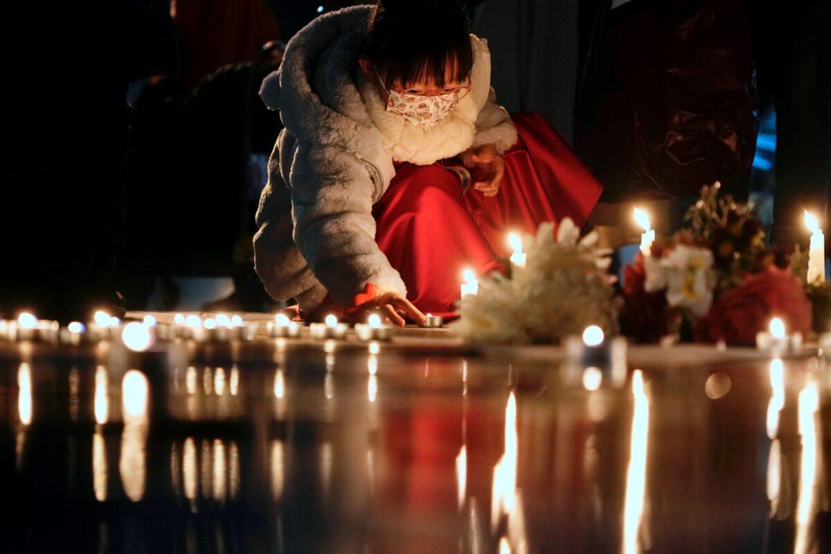 A girl lights candles at the site after the "Goddess of Democracy" statue, a memorial for those killed in the 1989 Tiananmen Square massacre, was removed from the Chinese University of Hong Kong on Dec. 24, 2021. (Vincent Yu/AP Photo)