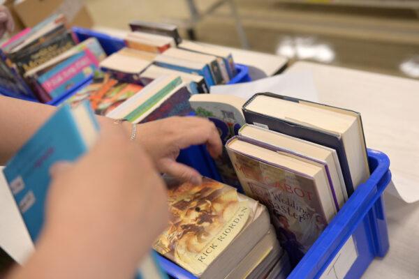 A schoolteacher collects library books from students who just graduated and but borrowed them before schools were shut down at a school in New York City on June 29, 2020. (Michael Loccisano/Getty Images)