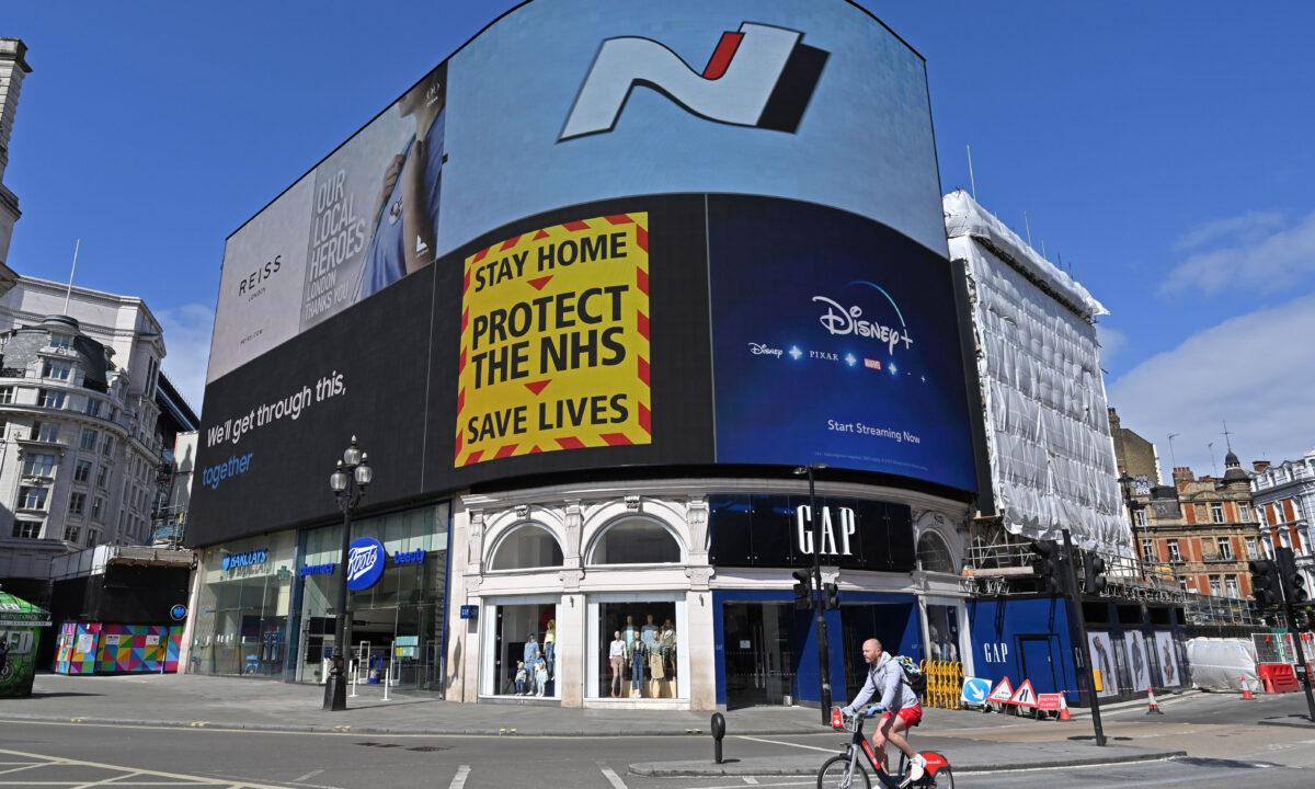 A government sign advising people to "Stay Home, Protect the NHS, Save Lives" is displayed on the advertising boards in Piccadilly Circus in London on April 13, 2020. (Glyn Kirk/AFP via Getty Images)