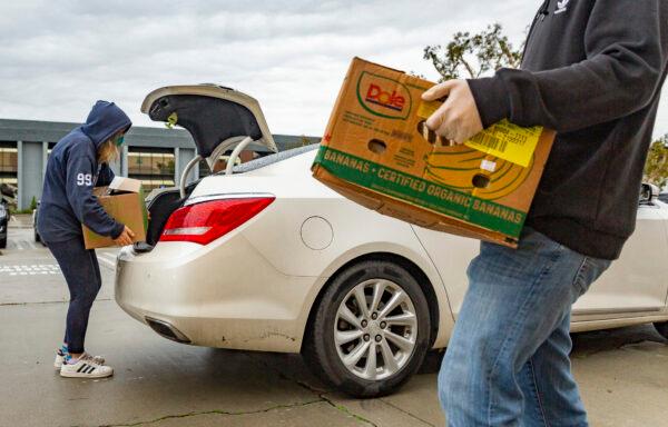 Volunteers at Laguna Niguel Presbyterian work with San Clemente-based Family Assistance Ministries to hand out food donations to a line of cars in Laguna Niguel, Calif., on Dec. 23, 2021. (John Fredricks/The Epoch Times)