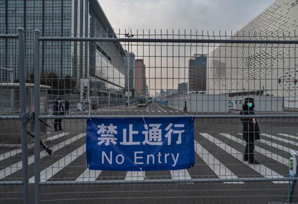 Security guards stand inside a fenced area next to the Main Media Center at Olympic Park in Beijing on January 19, 2022. (Kevin Frayer/Getty Images)