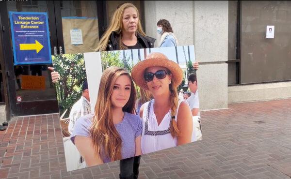 Gina McDonald holds a poster of herself and her daughter at the protest in front of the Tenderloin Linkage Center in San Francisco on Feb. 5, 2022. (Cynthia Cai/The Epoch Times)