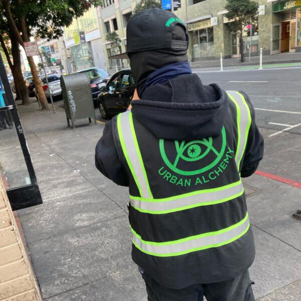 A person in an Urban Alchemy jacket stands on a San Francisco street on Jan. 5, 2022. (Steve Ispas/The Epoch Times)