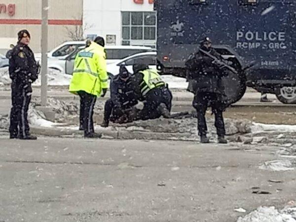 Police make an arrest at the Ambassador Bridge in Windsor, Ont., while trying to clear a blockade at the Canada-U.S. border crossing, on Feb. 13, 2022. (Lisa Lin/The Epoch Times)