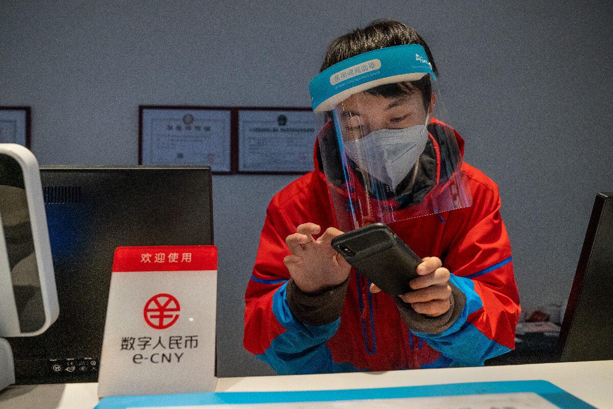 A worker at the front desk of Prince Ski Town Hotel checks the phone behind a sign saying "digital renminbi (e-CNY) is accepted" in Zhangjiakou, China, on Dec. 4, 2021. (Andrea Verdelli/Getty Images)