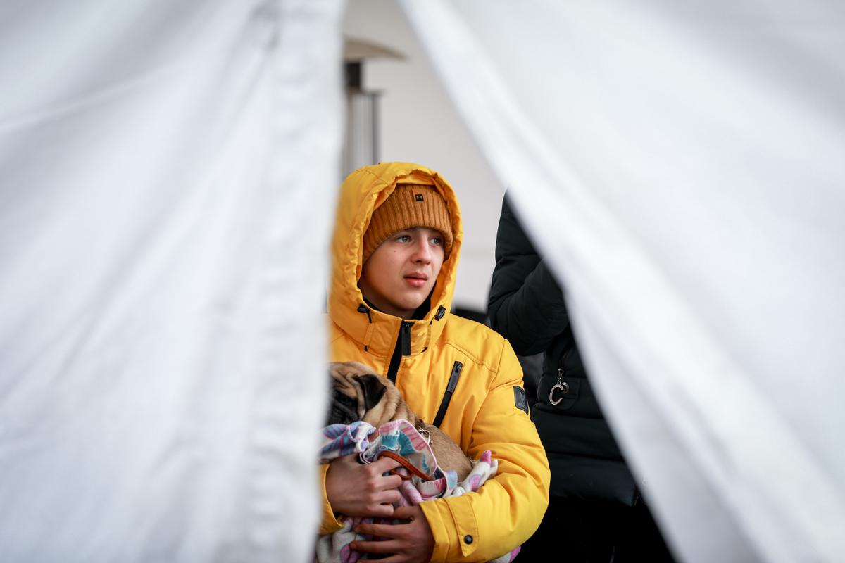 A young Ukrainian refugee holds his dog in a tent after arriving in Poland through the Medyka border crossing on March 10, 2022. (Charlotte Cuthbertson/The Epoch Times)