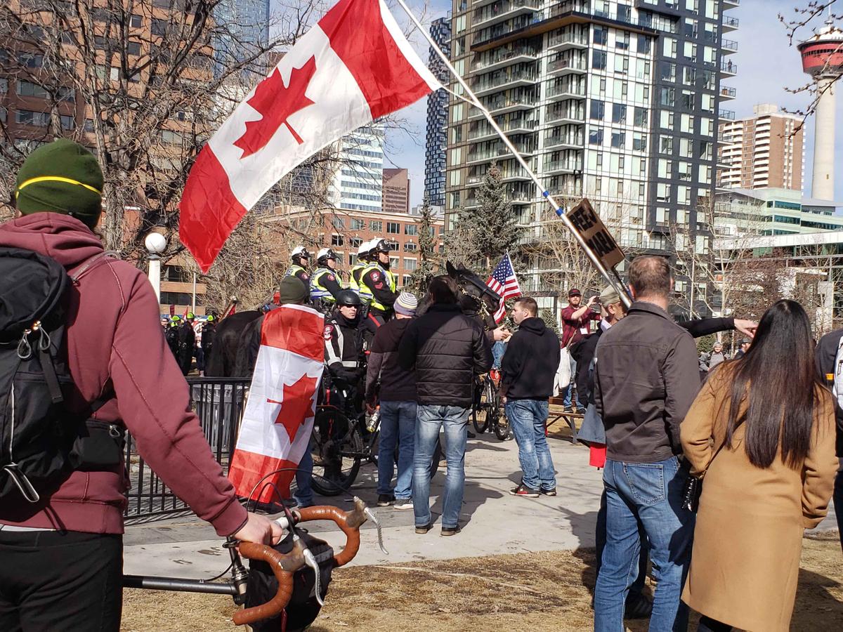 Protesters opposed to government COVID-19 mandates gather for a rally while mounted and bicycle police officers look on, at Central Memorial Park in the Beltline neighbourhood of Calgary on March 19, 2022. (Michael Wing/The Epoch Times)