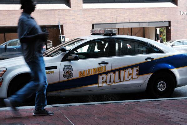 A person walks past a police car in Baltimore on July 28, 2019. Baltimore has a stubborn crime problem and has one of the highest murder rates in the nation for a city of any size. (Photo by Spencer Platt/Getty Images)