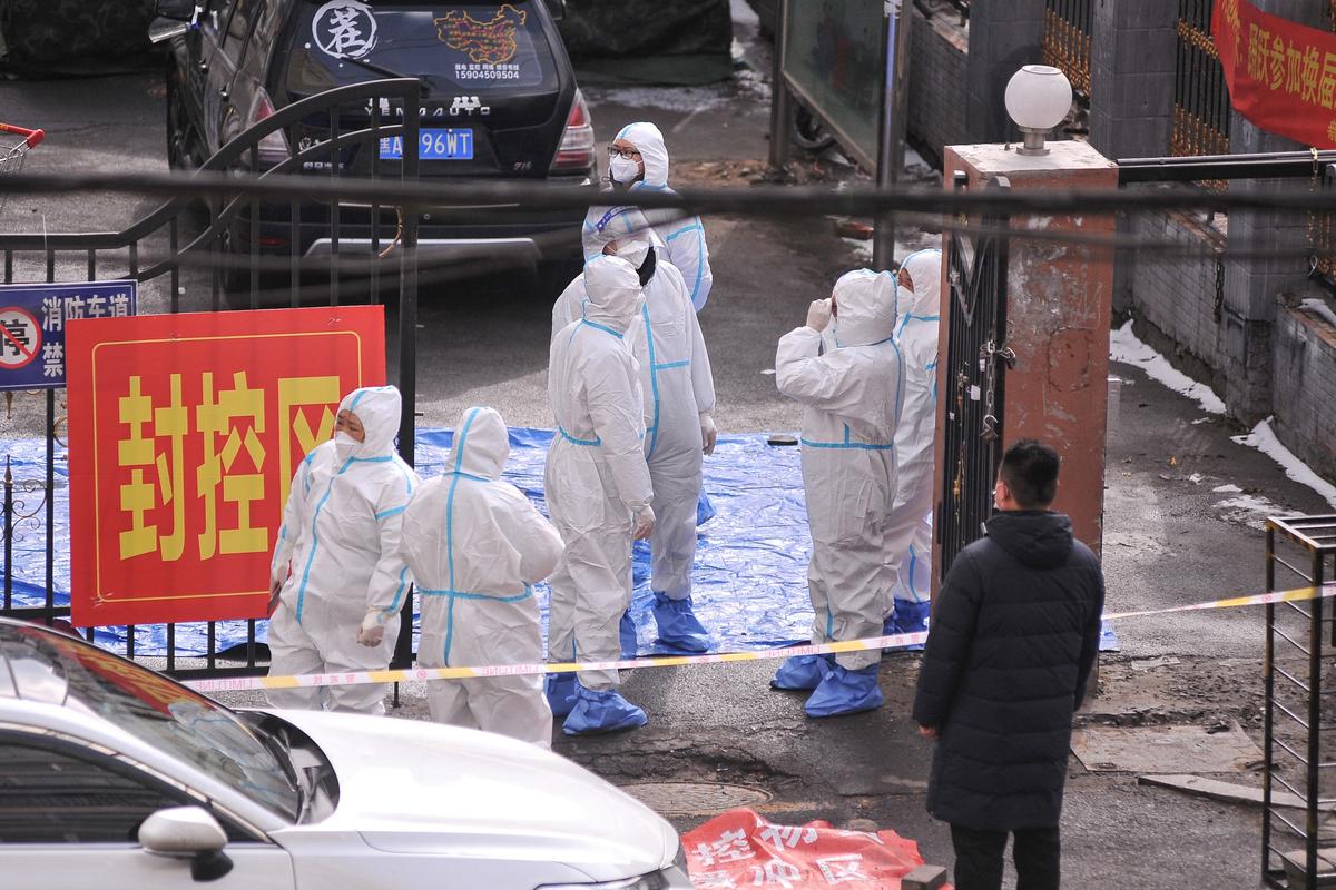 Staff members wearing personal protective equipment (PPE) stand at the entrance to a residental area which is restricted due to a recent outbreak of the Covid-19 coronavirus in Harbin in China's northeastern Heilongjiang province on March 15, 2022. (STR/AFP via Getty Images)