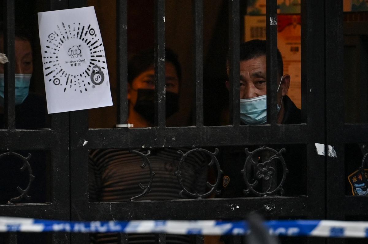 Residents look at the street from their neighborhood where barriers are being placed around to close off streets around after the detection of new cases of Covid-19 in Shanghai on March 15, 2022. (Hector Retamal/AFP via Getty Images)