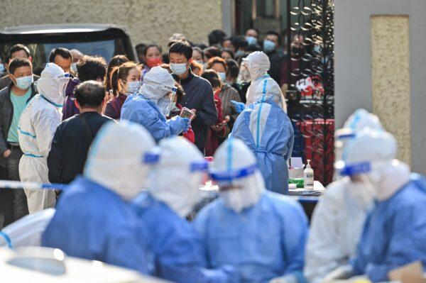 Health workers wearing protective gear prepare equipment in preparation for testing people for the COVID-19 coronavirus at a compound in Shanghai on March 23, 2022. (Hector Retamal/AFP via Getty Images)