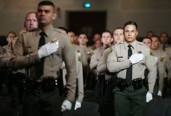 Graduates of Los Angeles County Sheriff's Department Academy stand for the pledge of allegiance at their graduation ceremony at East Los Angeles College in Monterey Park, Calif., on Aug. 21, 2020. (Mario Tama/Getty Images)