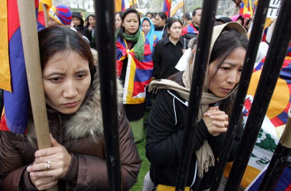 Protesters stand around the gates of a stage while holding a demonstration urging then-U.S. President George W. Bush to cancel his plans to attend the opening ceremonies of the 2008 Summer Olympics in Beijing at Lafayette Park across the street from the White House in Washington on March 31, 2008. (Saul Loeb/AFP via Getty Images)