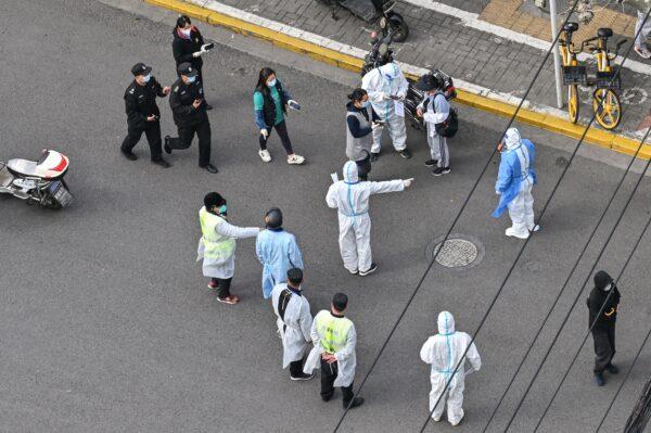 A health worker (C) wearing personal protective gear gestures to residents on a street during the second stage of a COVID-19 lockdown in Jing'an district in Shanghai on April 1, 2022. (Hector Retamal/AFP via Getty Images)