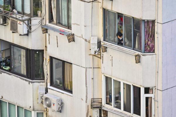A woman looks out of an apartment during a COVID-19 lockdown in the Jing'an District in Shanghai on April 9, 2022. (Hector Retamal/AFP via Getty Images)