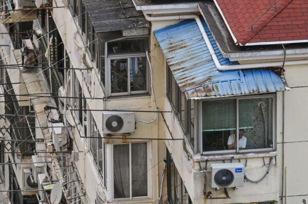 A man looks outside from his window during a COVID-19 lockdown in the Jing'an district in Shanghai on April 12, 2022. (Hector RetamalL/AFP via Getty Images)