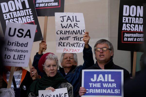 Wikileaks founder Julian Assange supporters hold placards as they gather outside Westminster Magistrates court In London, on April 20, 2022. (Alastair Grant/AP Photo)