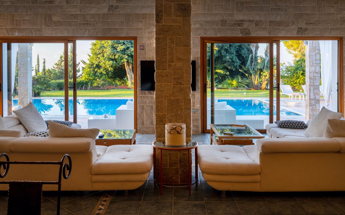 Well-designed living areas on the pool level open up onto a vast terrace and manicured lawns overlooking the sea. (Courtesy of Greece Sotheby's International Realty)