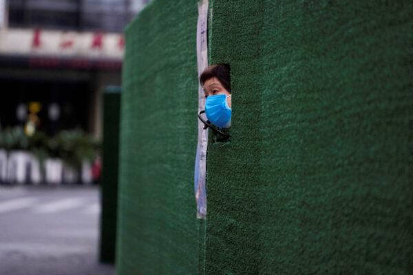 A resident looks out through a gap in the barrier at a residential area during lockdown in Shanghai on May 5, 2022. (Aly Song/Reuters)