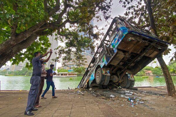 People take pictures of a burnt bus near Sri Lanka's former prime minister Mahinda Rajapaksa's official residence, a day after it was torched by protesters in Colombo on May 10, 2022. (Ishara S. Kodikara/AFP via Getty Images)