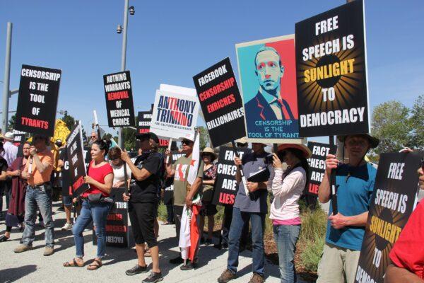 Protesters hold signs denouncing Facebook and CEO Mark Zuckerberg at the Humanity Against Censorship rally in front of Meta headquarters in Menlo Park, Calif. on May 19, 2022. (Hao Qiuyan/The Epoch Times)