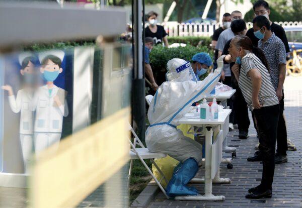 A health worker takes a swab sample from a woman to be tested for the COVID-19 coronavirus at a swab collection site in Beijing on May 23, 2022. (Noel Belis/AFP via Getty Images)