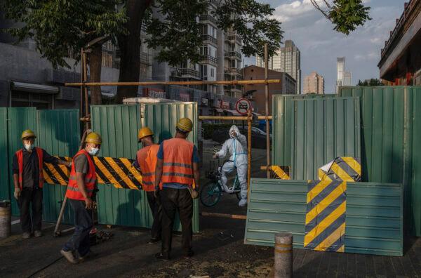 A worker wearing protective clothing instructs workers as they erect a barrier wall around a residential community in lockdown after recent COVID-19 outbreaks in Beijing on May 24, 2022. (Kevin Frayer/Getty Images)