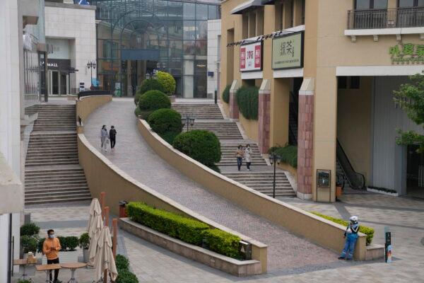 A delivery man waits in a quiet mall area in Beijing with closed retail shops and restaurants offering takeaway on May 10, 2022. (AP Photo/Ng Han Guan)