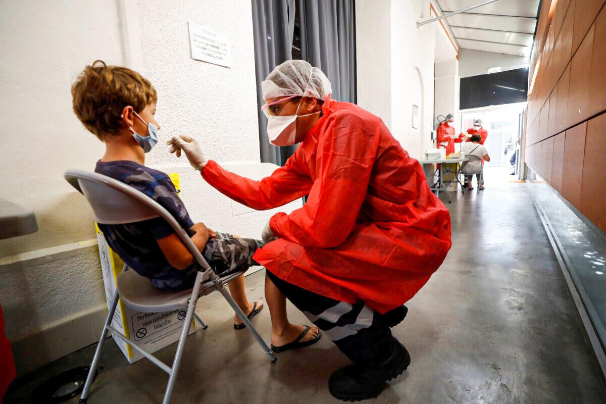 A firefighter from the Marseille Naval Fire Battalion administers a nasal swab to a child at a testing site for COVID-19 in Marseille, France, on Sept. 17, 2020. (Eric Gaillard/Reuters)