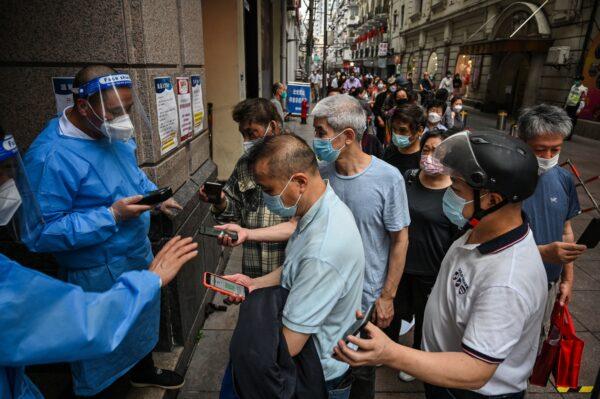 Workers scan QR health codes of people entering a shopping mall in the Huangpu district of Shanghai on June 1, 2022. (Hector Retamal/AFP via Getty Images)