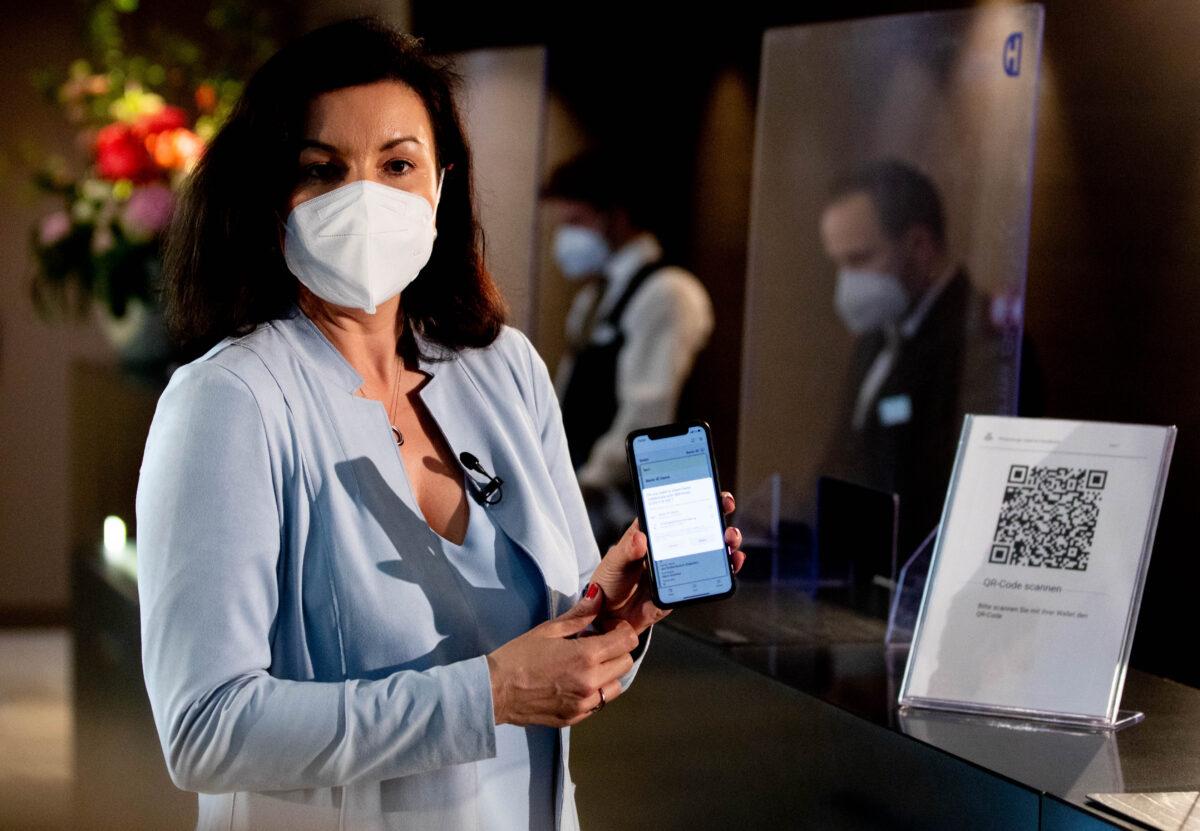Dorothee Baer, German minister of state to the federal chancellor and federal government commissioner for digitisation, shows an ID wallet on display on the screen of a mobile phone at a reception at the Steigenberger Hotel in Berlin on May 17, 2021. (Filip Singer/Getty Images)