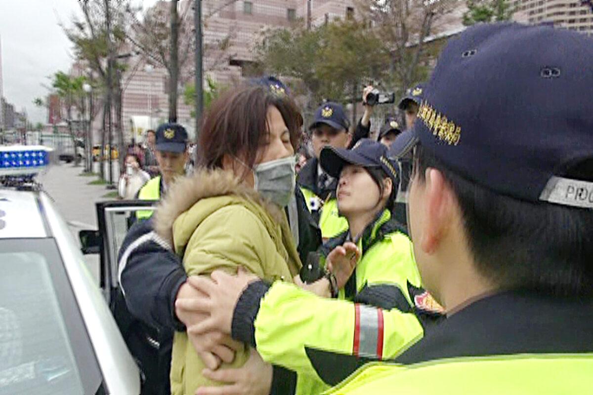 Zhang Xiuye (masked), a member of the pro-Beijing group Patriot Alliance Association, is arrested outside Taipei 101 building for harassing Falun Gong practitioners on March 6, 2015. (minghui.org)