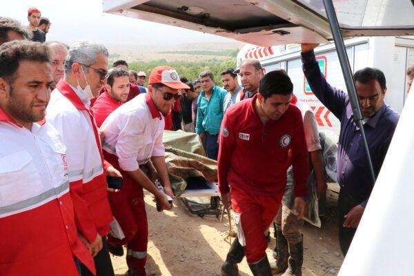 Members of a rescue team load the body of a victim to an ambulance after Friday's flash floods in Iran's drought-stricken southern Fars Province, Iran, on July 23, 2022. (Iranian Red Crescent Society via AP)