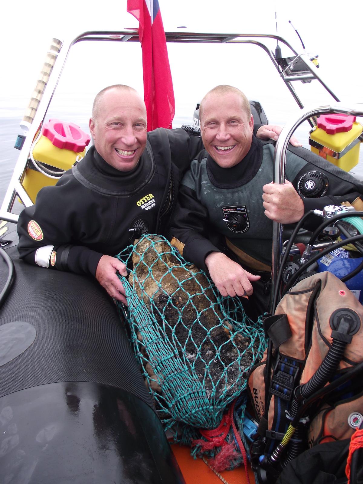 (L–R) Brothers Julian and Lincoln Barnwell with the ship's bell. (Courtesy of Norfolk Historic Shipwrecks)