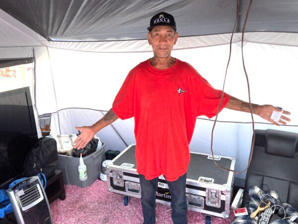Fernando Sanchez shows off the contents of his tent enclosure set up on Skid Row in downtown Los Angeles on July 26, 2022. (Allan Stein/The Epoch Times)