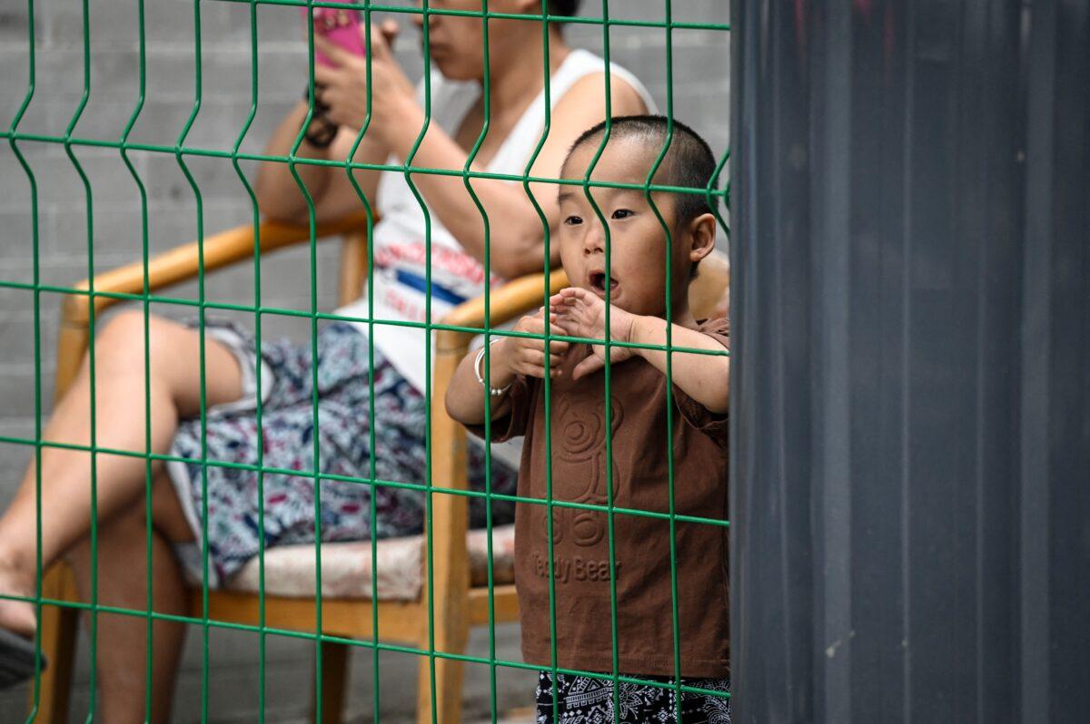 A boy stands behind a fence of a residential area under COVID-19 lockdown in Beijing on June 14, 2022. (Jade Gao/AFP via Getty Images)