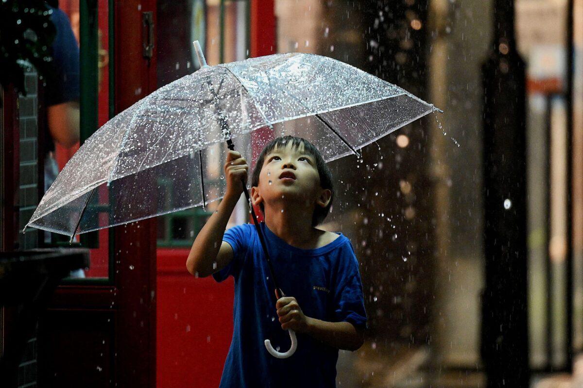 A boy uses an umbrella in Nanlouguxiang Alley in Beijing on July 27, 2022. (Noel Celis/AFP via Getty Images)