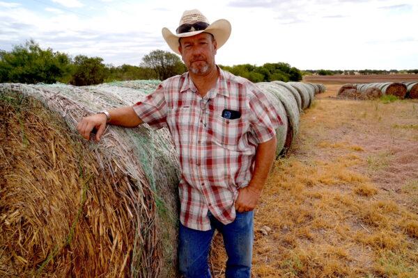 Cattleman Kyle Foster leans against a rolled hay bale on Aug. 9, 2022. Foster said he normally keeps a two-year supply of hay in case of unforeseen circumstances, including drought. (Allan Stein/The Epoch Times)